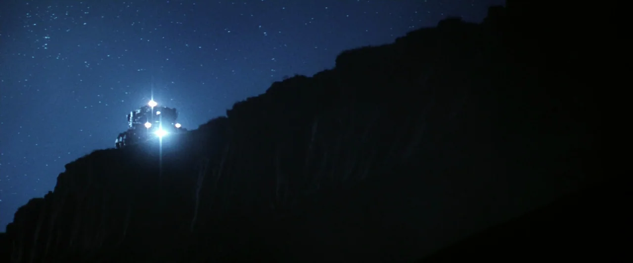 Armageddon (1998) movie still: wide — A steam locomotive silhouetted against a deep blue, star-filled sky at night. The train travels along the…