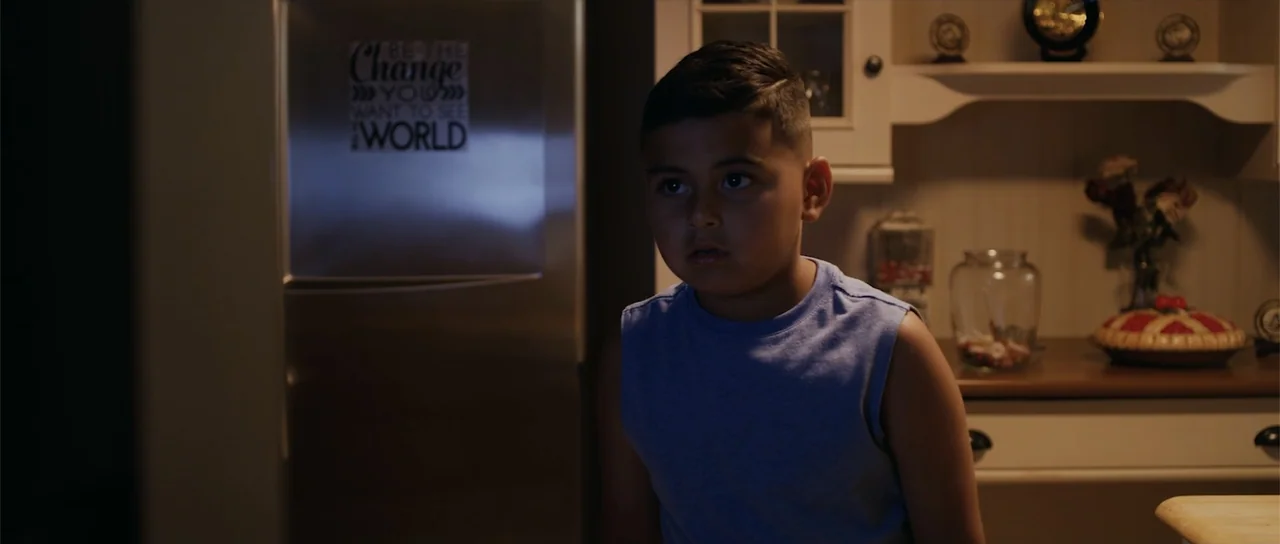 Night of the Missing (2023) movie still: medium — A residential kitchen interior features a stainless steel refrigerator and white cabinetry. A…