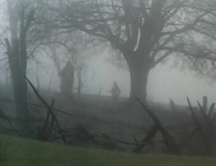 The Wishing Tree (1977) movie still: wide — A dense foggy field contains several large leafless trees and a splintered wooden fence. Silhouetted…