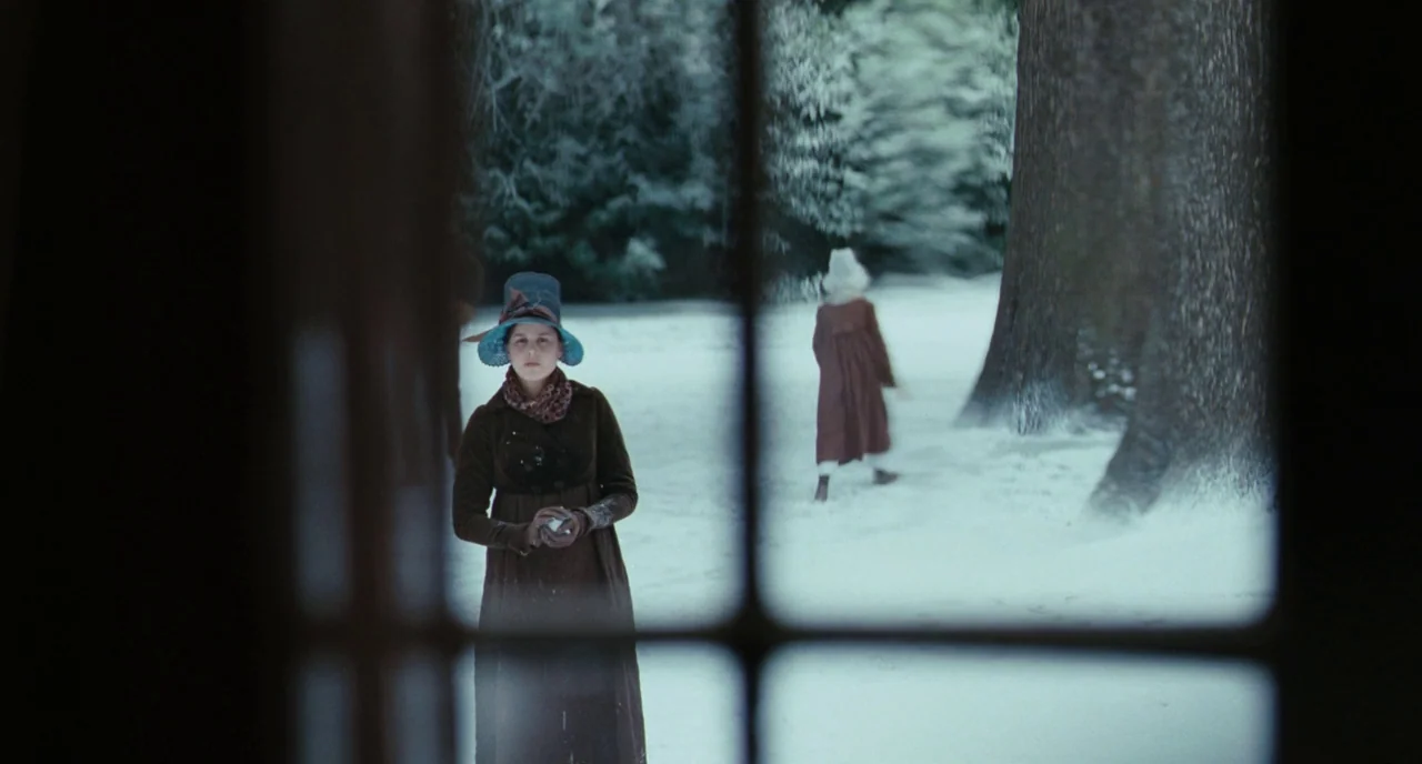 Bright Star (2009) movie still: medium — A snowy, tree-lined area is framed through a dark multi-pane window structure. A woman in a dark dress…