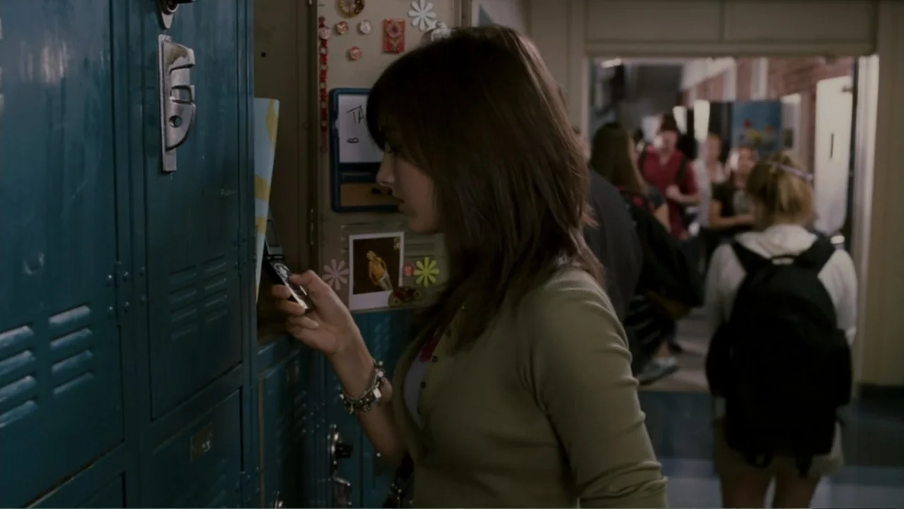 When a Stranger Calls (2006) movie still: medium — A high school hallway features rows of dark teal metal lockers on the left. A young woman stands…