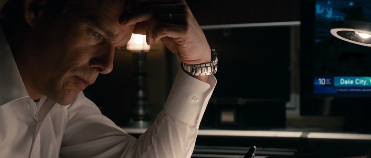 The Purge (2013) movie still: closeup — A dark study at night features a man working at a dimly lit desk. He rests his forehead against his fingers…
