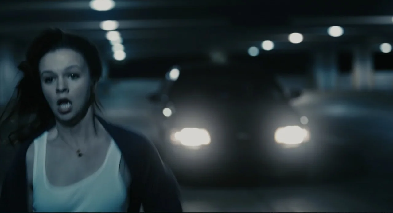 Beyond a Reasonable Doubt (2009) movie still: medium — A dark concrete parking structure features bright approaching car headlights in the…
