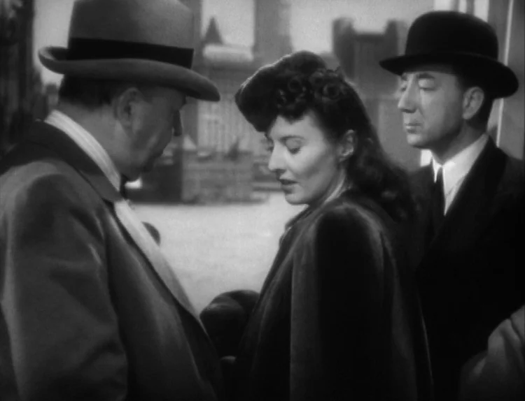 The Lady Eve (1941) movie still: medium — An outdoor city setting features brick buildings in the background under daylight. Two men wearing hats…