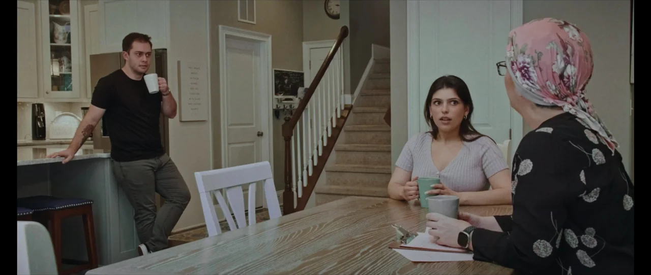 Ordinary Things (2001) movie still: medium — A residential open-plan kitchen and dining area features wooden cabinetry, white trim, and a staircase.…