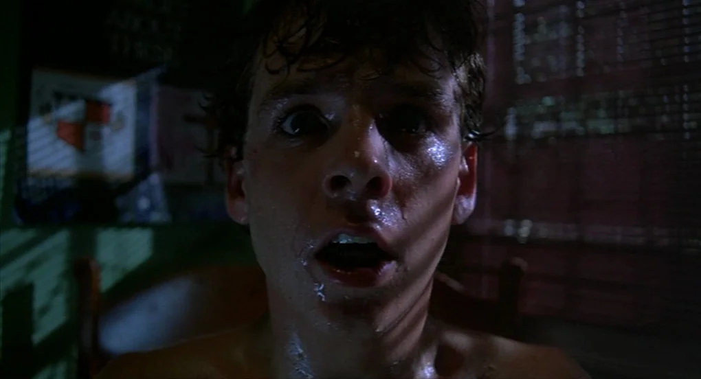 A Nightmare On Elm Street 2: Freddy’s Revenge (1985) movie still: closeup — A dimly lit room with blinds partially obscuring a light source from…
