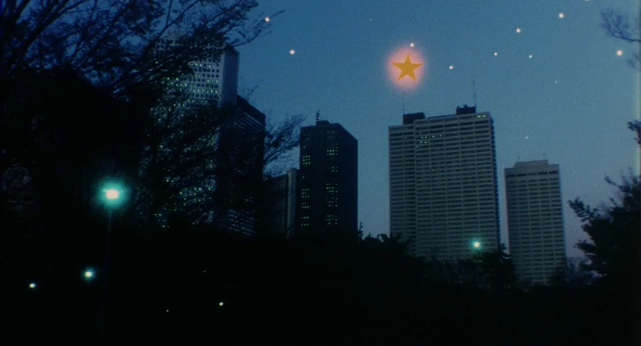School in the Crosshairs (1981) movie still: establishing — A dark city skyline with tall office buildings rises above a silhouette of trees at…