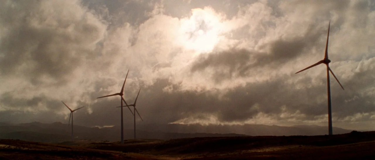 Arabian Nights: Volume 1 – The Restless One (2015) movie still: wide — A rural landscape features several large white wind turbines set against a…