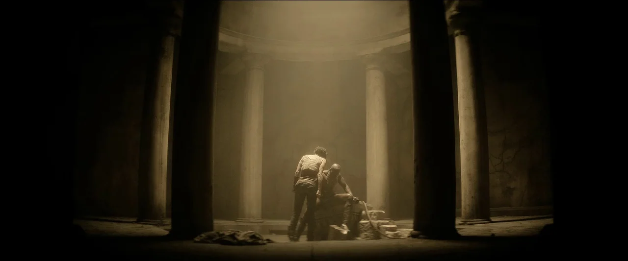 Rebel Moon – Part One: A Child of Fire (2023) movie still: wide — A large circular stone structure features towering columns and dust particles in…