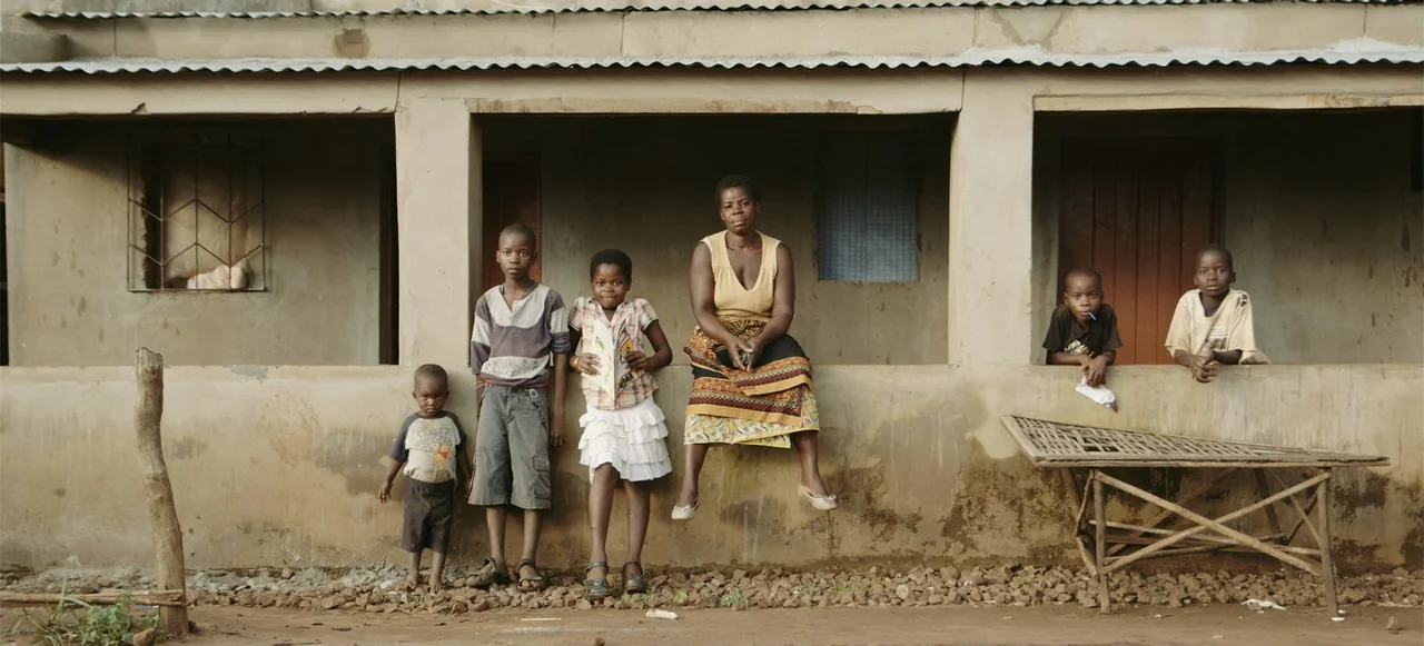 10 Billion: What's On Your Plate (2015) movie still: fullbody — A group of six people sit and stand along a weathered concrete wall foundation. The…