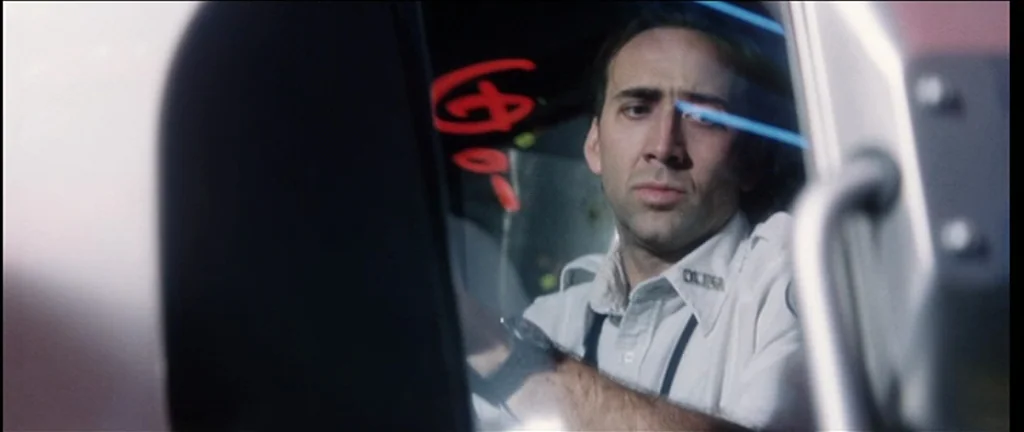 Bringing Out The Dead (1999) movie still: closeup — An ambulance cab at night with a red symbol marked on the side window. A man in a uniform looks…