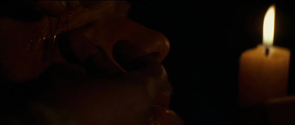Unforgiven (1992) movie still: closeup — A person performs a delicate task using a needle in a dark, candlelit space. The subject's face is…