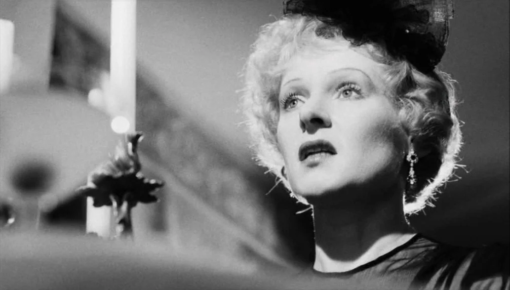 Veronika Voss (1982) movie still: closeup — An interior space is dimly lit by a nearby candle. A woman gazes upward with a fixed expression.