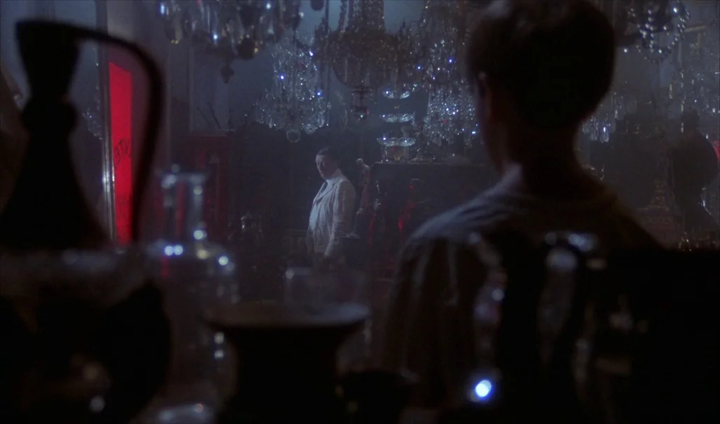 Fanny and Alexander (1982) movie still: medium — An interior antique shop filled with numerous crystal chandeliers hangs in the dark air. A man in a…