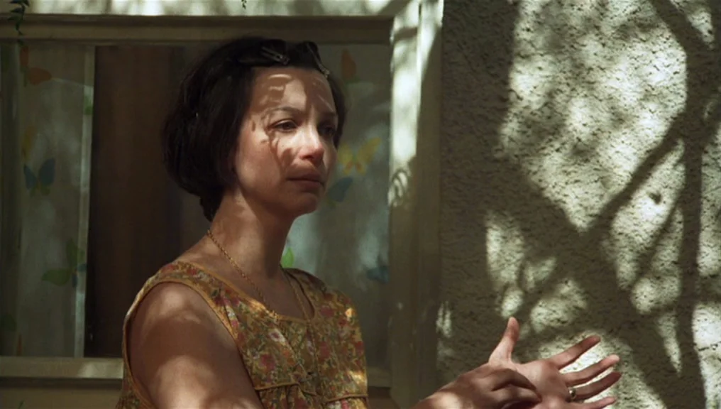 Alice Doesn’t Live Here Anymore (1974) movie still: medium — A woman stands in front of a stucco wall near a window. She gestures with her hands…