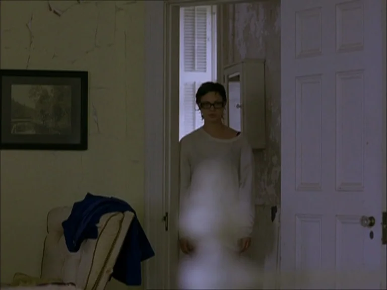 Last Days (2005) movie still: medium — A hallway with peeling yellow paint connects two rooms with white wooden doors. A young woman stands in the…