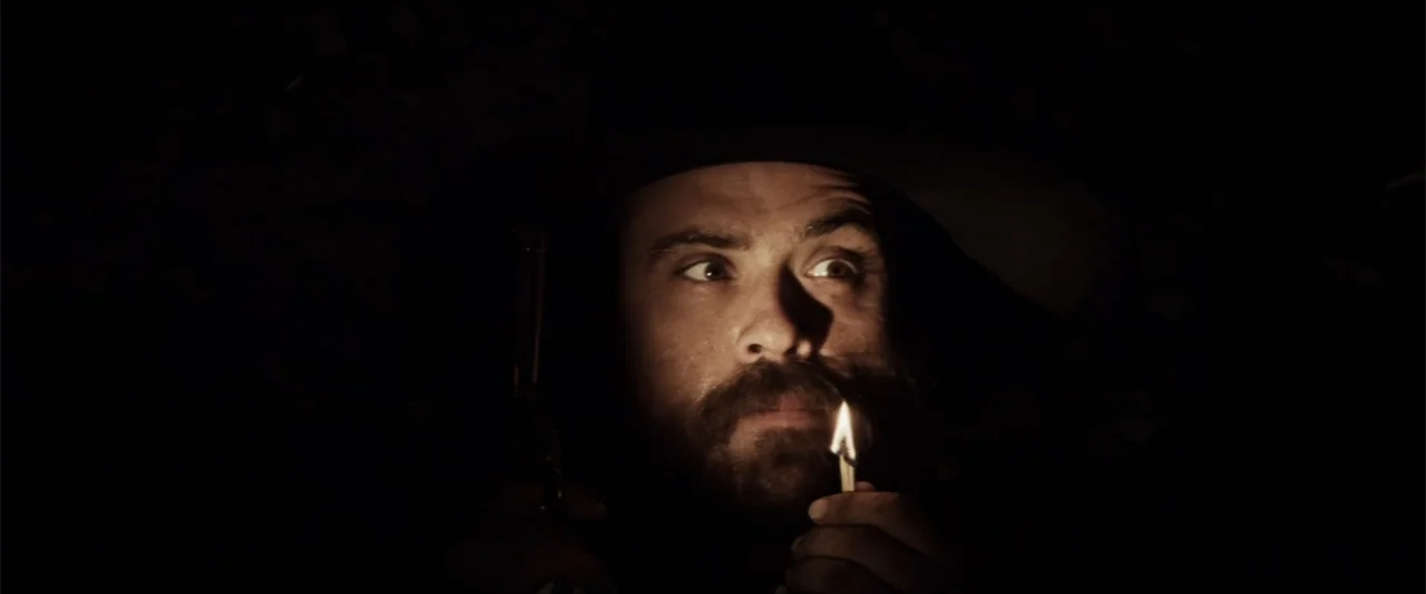 Matar o morir (1984) movie still: closeup — A dark, unlit interior space where the only illumination comes from a single match. A man in a dark hat…