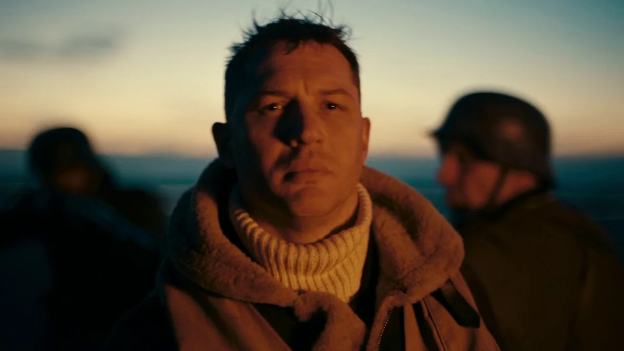 Dunkirk (2017) movie still: closeup — The interior of a military aircraft cockpit during a sunset flight over a dark sea. A man in a shearling…