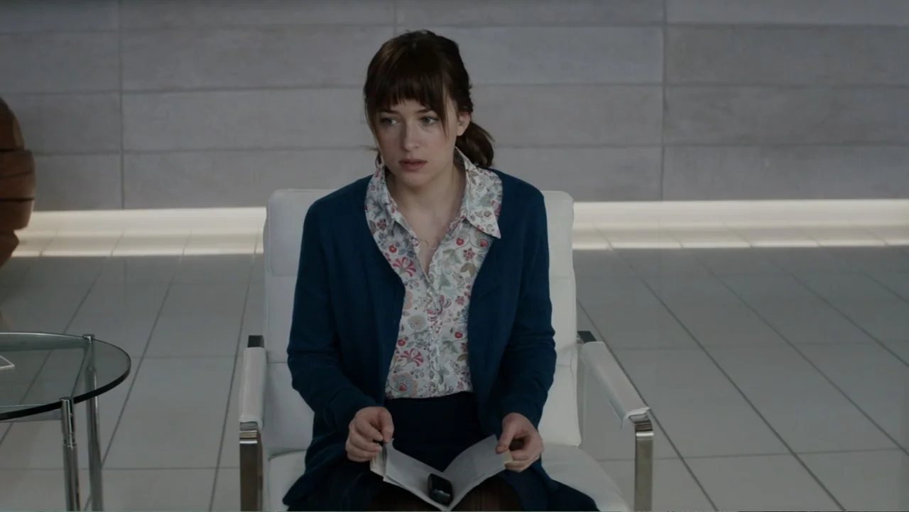 Fifty Shades of Grey (2015) movie still: medium — A minimalist office waiting area with glossy white tiled floors and paneled walls. A young woman…