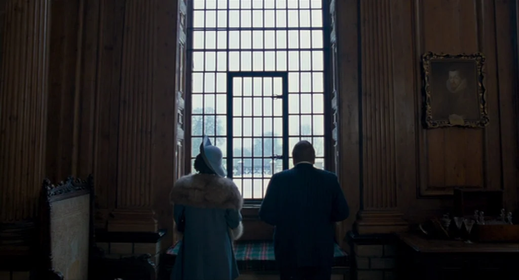 The King’s Speech (2010) movie still: medium — A dark paneled room features a tall grid window and a vintage oil portrait. Two figures stand before…