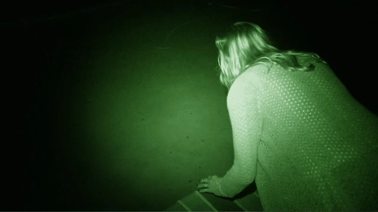 Paranormal Activity: The Ghost Dimension (2015) movie still: medium — A dark night rooftop is illuminated by a narrow green infrared light beam. A…
