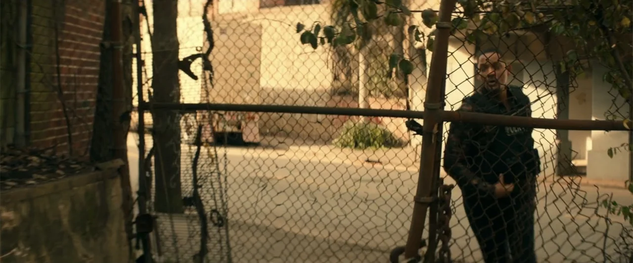 Bad Boys for Life (2020) movie still: medium — An outdoor area features a tall chain link fence separating the foreground from space. A man in a…