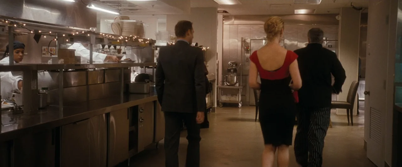 Life As We Know It (2010) movie still: fullbody — A stainless steel industrial food preparation area contains several employees wearing white…