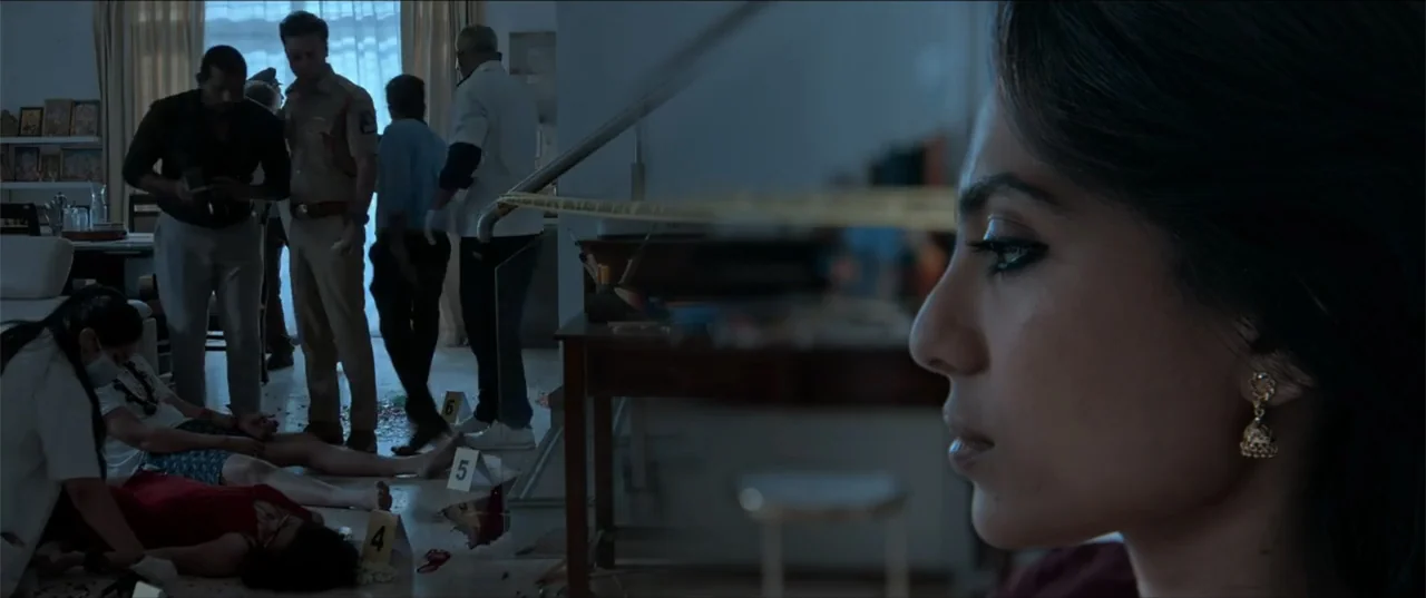 Cheekatilo (2026) movie still: medium — A residential living area contains forensic markers and police investigators documenting a crime scene. In…