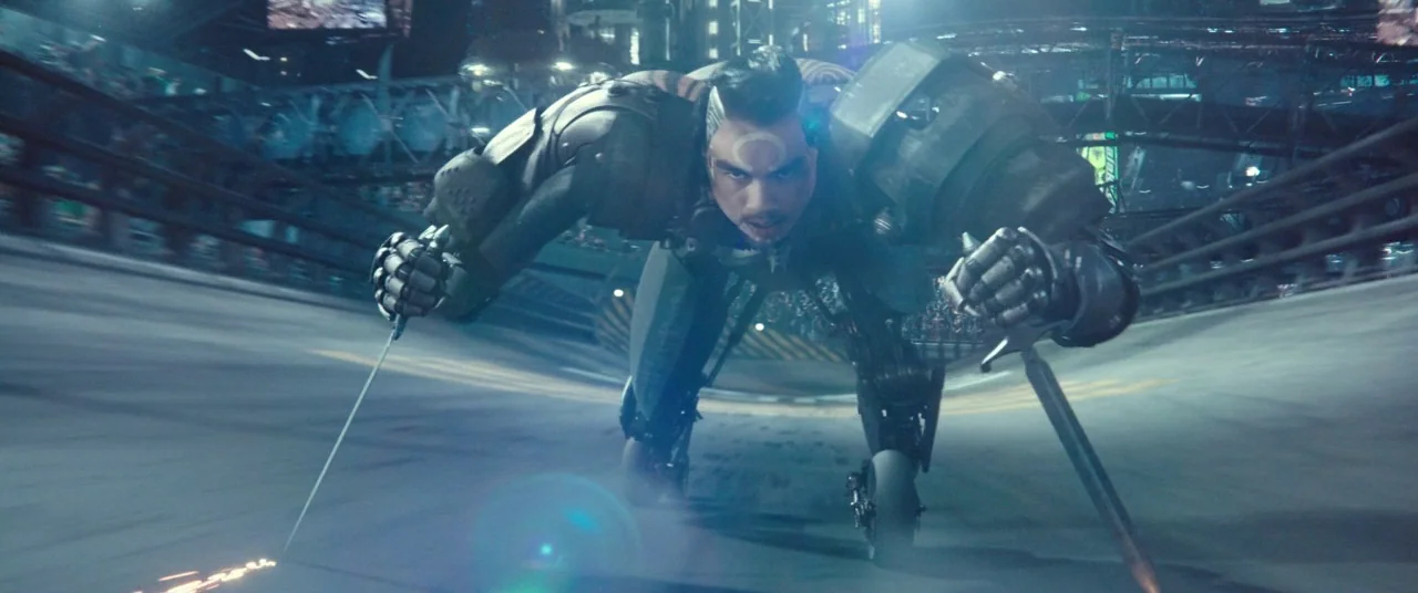 Alita: Battle Angel movie still: medium — A futuristic racing track at night with metallic structures under bright artificial spotlights. A cyborg…