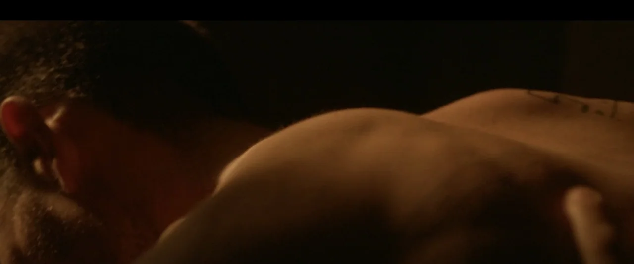 One Fast Move (2024) movie still: closeup — A dimly lit interior room features the upper torso and head of a person. The subject lies in profile…