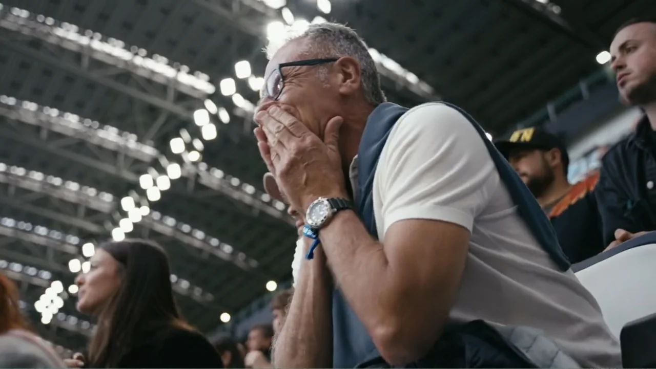 FRAGILE - The story of Nicolò Fagioli (2024) movie still: medium — A crowded sports stadium features high arched steel roof trusses visible above…