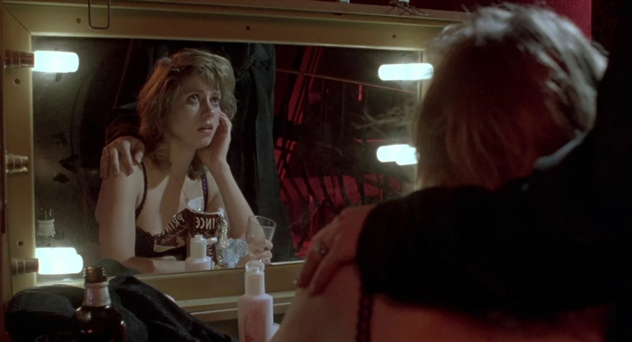 Three Colours: Blue (1993) movie still: medium — A dimly lit dressing room features a mirror surrounded by glowing incandescent light bulbs. A woman…