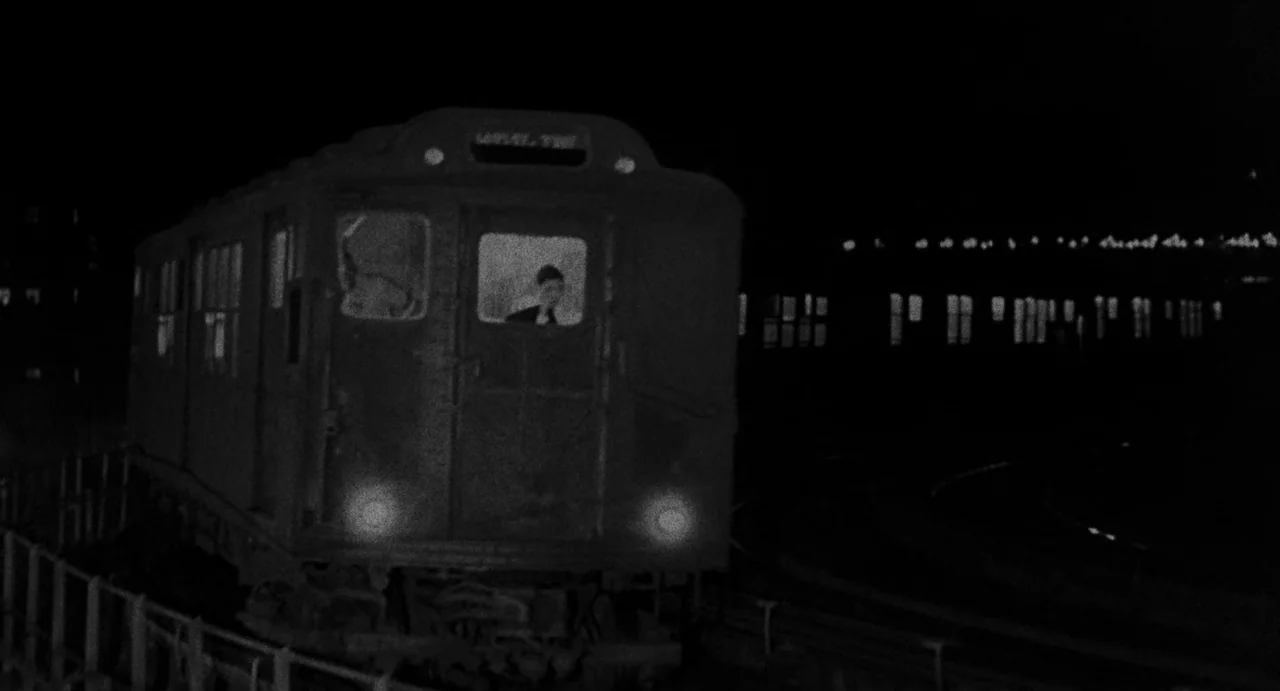 The Incident (1967) movie still: wide — An old train carriage moves along an elevated iron structure at night. Only the headlights and a small…