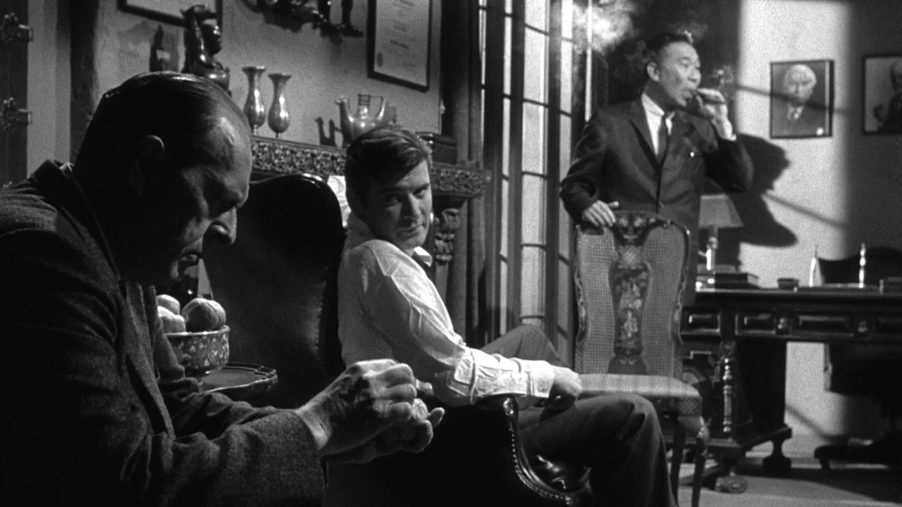 Shock Corridor (1963) movie still: medium — A wood-paneled room decorated with framed diplomas and portraits hanging on the walls. Three men are…