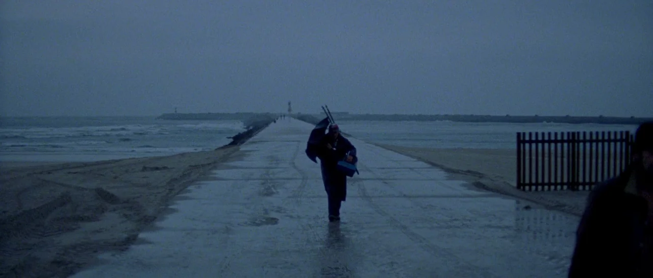 Arabian Nights: Volume 1 – The Restless One (2015) movie still: wide — A long wet concrete jetty stretches between a grey ocean and sand dunes. A…
