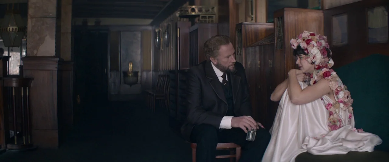 The Dancer movie still: medium — A dark, wood-paneled interior space features classic early 20th-century architectural details and furnishings. A…