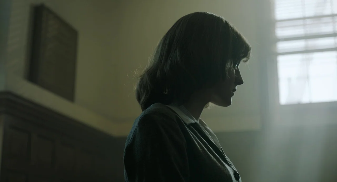 My Policeman (2022) movie still: medium — A dimly lit indoor space features wooden wall panels and a bright window. A young woman with…