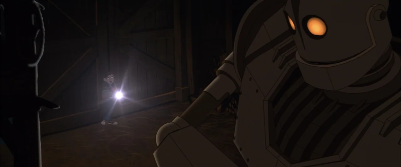The Iron Giant (1999) movie still: medium — A dark wooden barn interior houses a large metal robot and a young boy. The boy points a handheld…