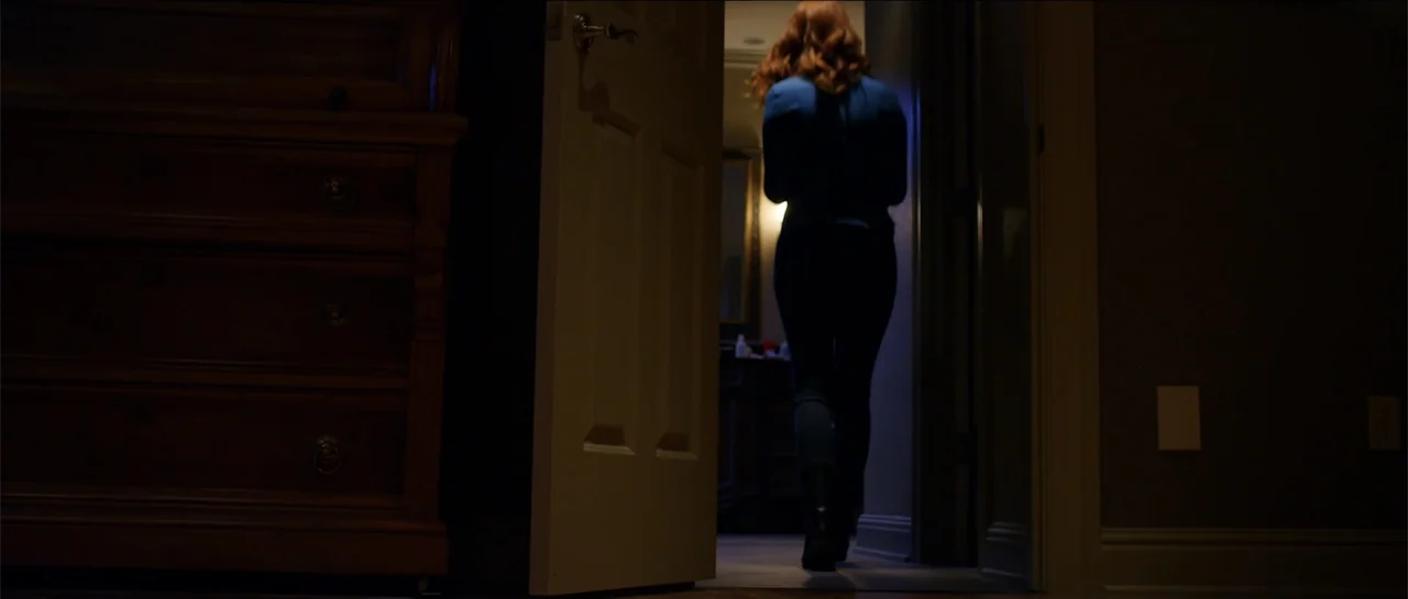 Halloween III: Season of the Witch (1982) movie still: fullbody — A dark, dimly lit domestic hallway leads into a brighter adjacent room through a…