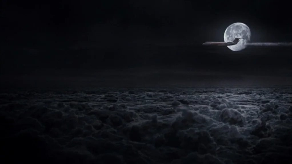 We Are The Night (2010) movie still: wide — A dark night sky view from above a thick layer of clouds. A small passenger airplane silhouette crosses…