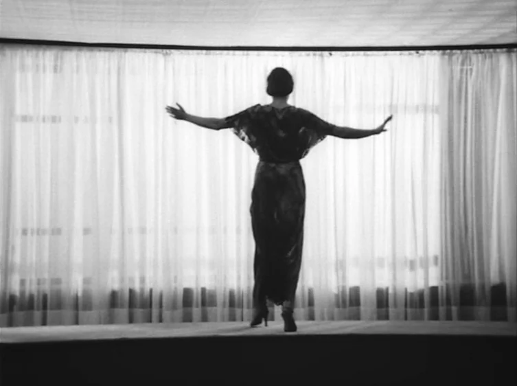 From the Life of the Marionettes (1980) movie still: fullbody — A spacious room features a large window covered by long, floor-to-ceiling sheer…