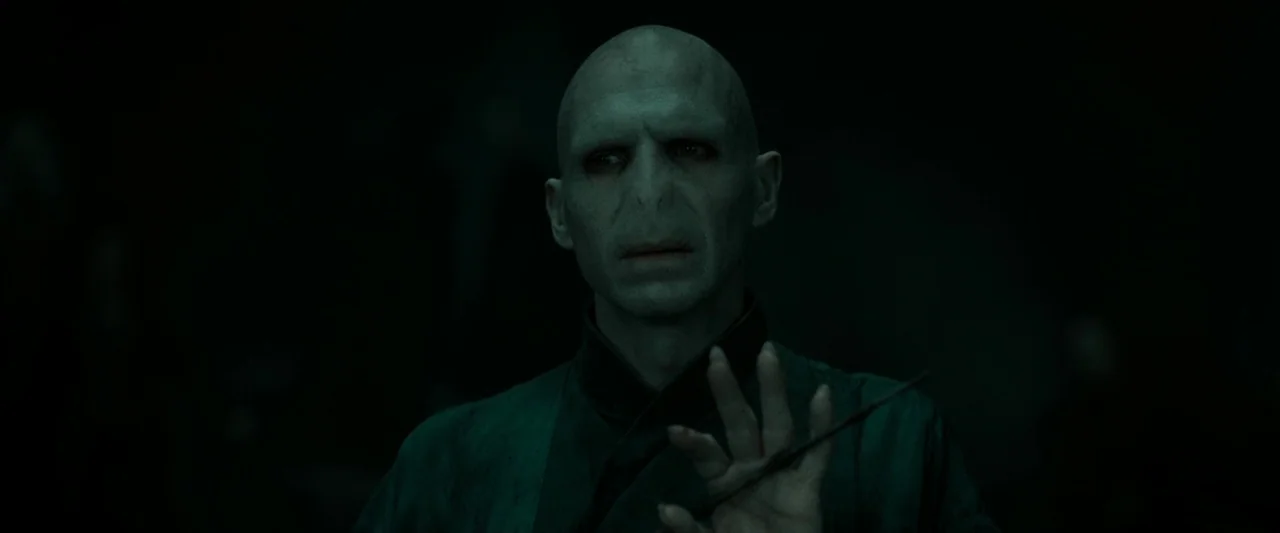 Harry Potter & The Deathly Hallows Part 2 (2011) movie still: medium — A dark, undefined space shrouded in heavy green light and shadows. A bald man…