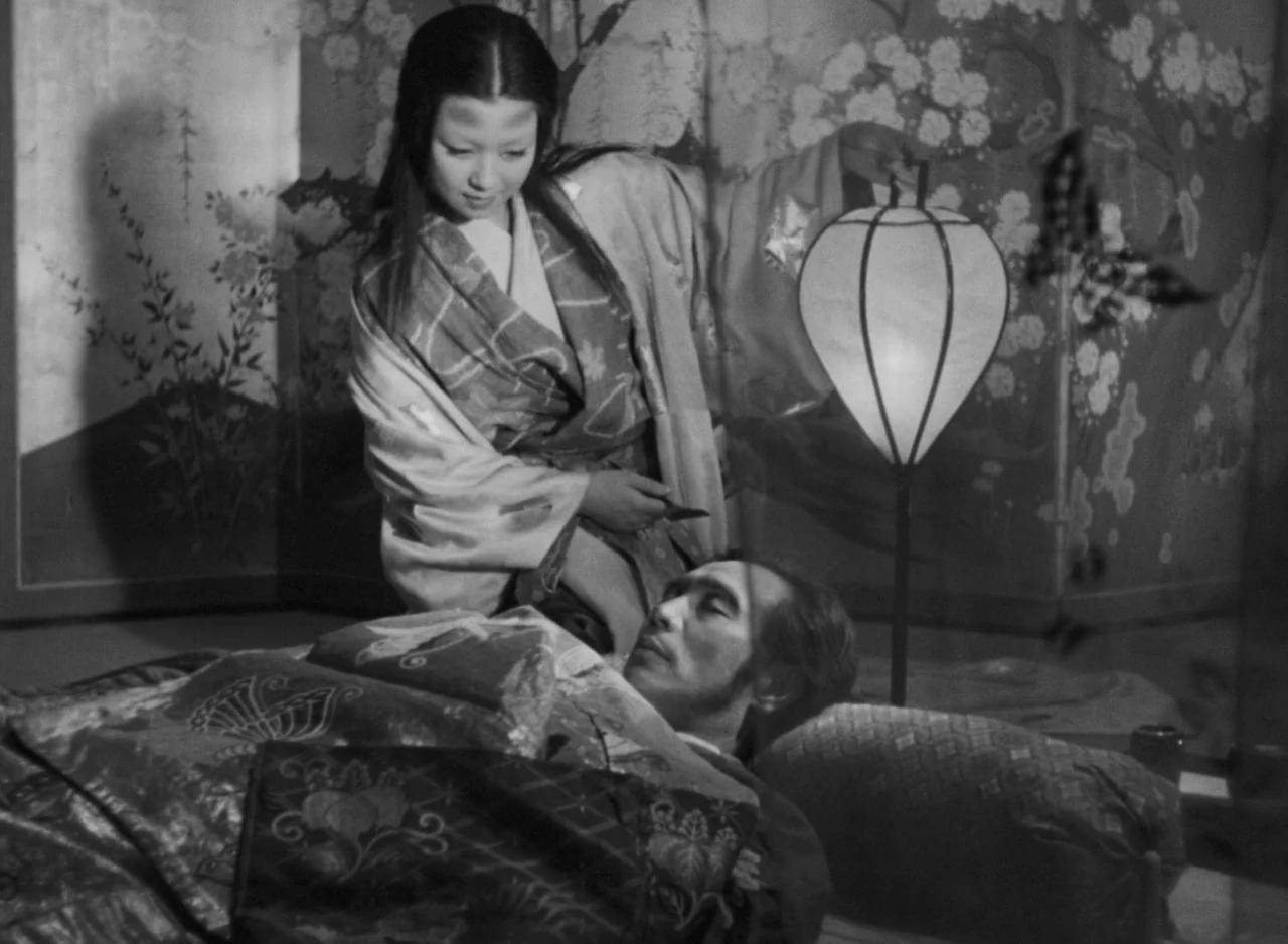 Ugetsu (1953) movie still: medium — An interior space features a decorated folding screen with floral illustrations in the background. A woman in a…