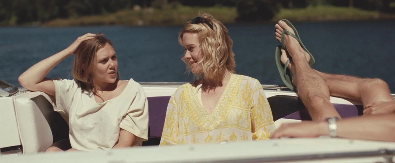 Martha Marcy May Marlene (2011) movie still: medium — Two women sit together on the white cushioned seating of a motorboat moving on water. One…