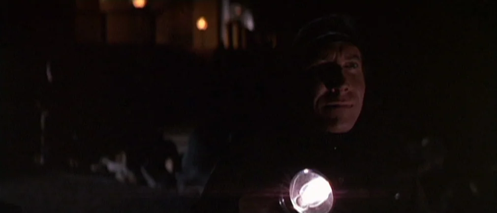 Boom! (1968) movie still: medium — An outdoor night environment is lit only by the glare of a handheld flashlight. A man in uniform stares into the…
