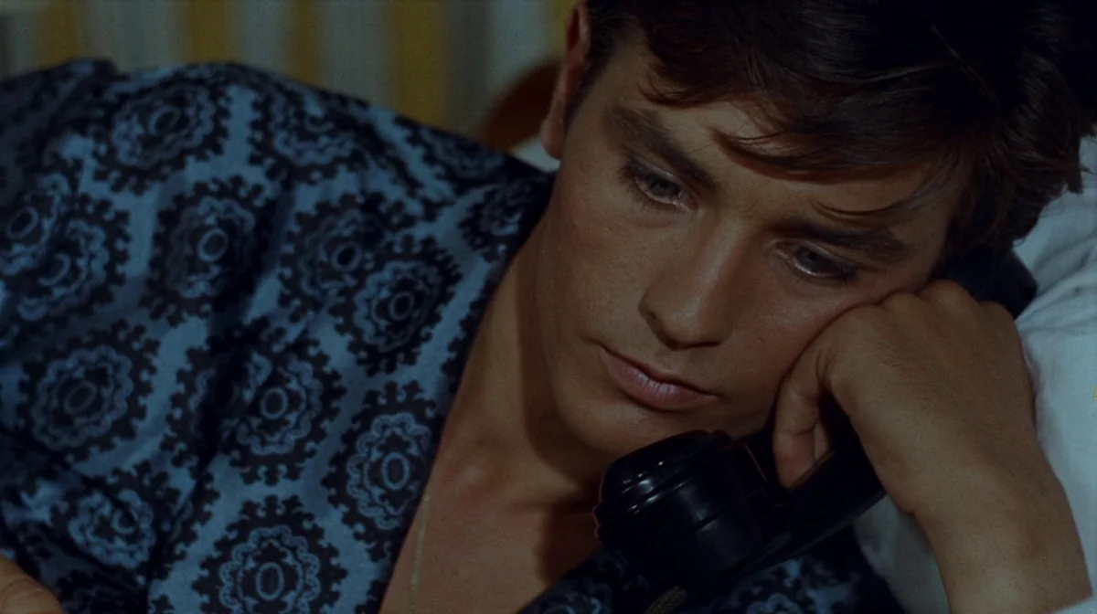 Purple Noon (Plein Soleil) (1960) movie still: closeup — A dark bedroom interior with soft lighting illuminating a young man. The man lies down on a…