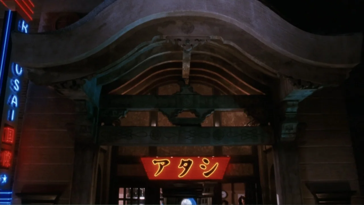 The Bodyguard (1992) movie still: establishing — The entrance to a building features ornate traditional Japanese architectural wood carvings.…