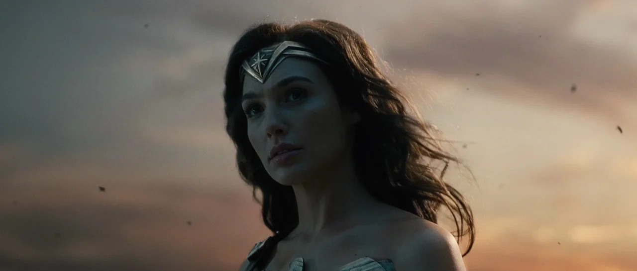Wonder Woman (2017) movie still: closeup — A woman stands in an open area during sunset with a cloudy, dim sky. She gazes past the camera frame…