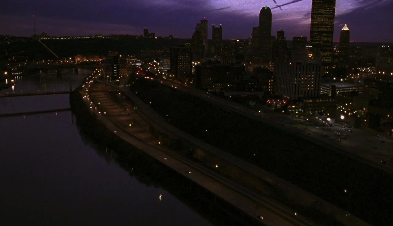 The Perks of Being A Wallflower (2012) movie still: establishing — An aerial night view overlooks a river and a curved highway leading toward a…