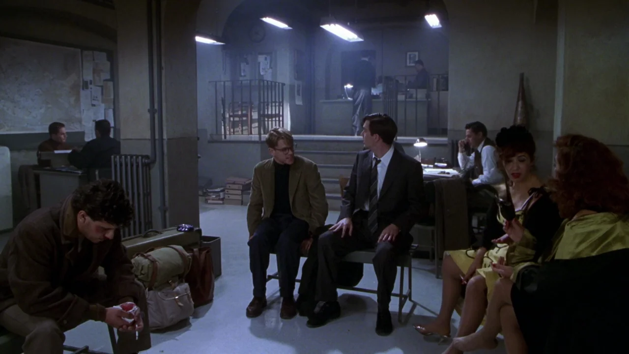 The Talented Mr. Ripley (1999) movie still: wide — A basement waiting room with concrete floors and industrial fluorescent lights overhead. Several…